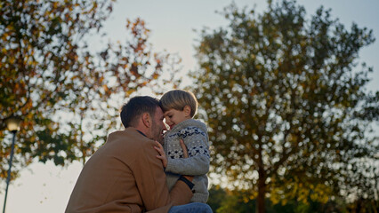 Fototapeta premium Father and son embrace outdoors in a park on a sunny autumn day