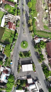 Static aerial top-down view of a Y-junction roundabout with light traffic flow in a small suburban town on a sunny day.
