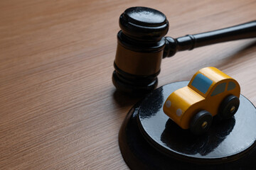 Toy car and a judge’s gavel. Automobile law, insurance claims, legal disputes, traffic court concept.