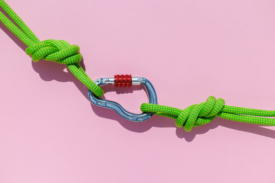rope with a secure knot and a carabiner lies on a colored background. Equipment for rock climbing and mountaineering. reliable connection. concept of reliability and strength.