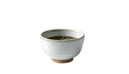 Dark sauce in a speckled white bowl, isolated on black background