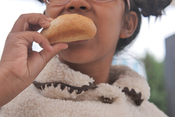 Child enjoying a baked treat outdoors in cozy attire