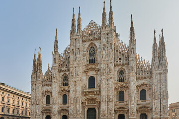 Naklejka premium The stunning Gothic facade of the Milan Cathedral (Duomo di Milano) dominates the square with its intricate spires and marble details. Architecture, landmark.