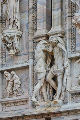 Detailed view of sculpted figures on the fa&ccedil;ade of the Milan Cathedral (Duomo di Milano), showcasing expressive marble statues and reliefs. architecture, sculpture