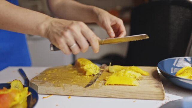 Mother slicing ripe mango for son in the kitchen