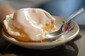 Partially eaten sweet pastry with white icing on a plate with a spoon.
