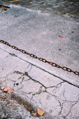 Obraz premium Rusted Metal Chain Barrier Across Cracked Concrete Ground