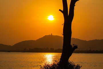 Fototapeta premium Amazing red sky in sunset at Phuket big Buddha. Phuket big Buddha in circle of the sun in red sky. The beauty of the statue fits perfectly with the charming nature.
