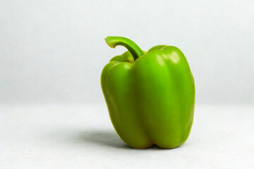 A single vibrant green bell pepper on a white background