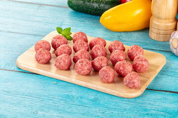 Raw beef meatballs over board