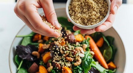 Close-up shot of two hands sprinkling sesame seeds over a vibrant mixed salad with vegetables in a white bowl on a clean white surface.
