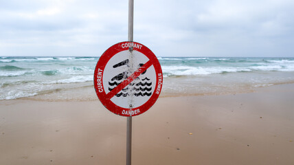 strong current courant stromer danger text warning sign on beach indicate in red panel of potential danger in sea ocean water