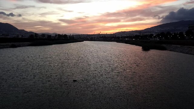 Sunset over the Oued Martil (formerly R&iacute;o Mart&iacute;n), birds flying along the valley, and the Tetouan skyline bathed in warm golden light, capturing the gentle curve of the valley, and the waterfront life