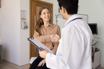 Obraz premium Young smiling Argentinian female patient and male doctor shaking hands