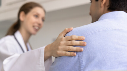 Fototapeta premium Compassionate female doctor gently touches male patient shoulder