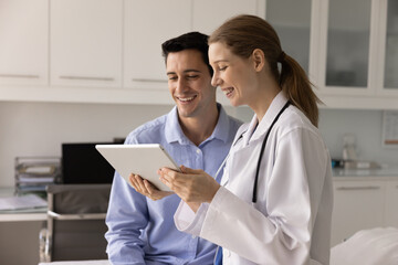 Obraz premium Nurse explains to male patient medical test results on tablet