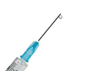 Isolated syringe with needle and drop of clear medicine in front of a plain backdrop