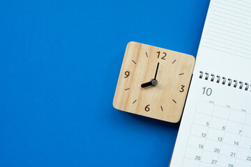 close up of calendar and alarm clock on the blue table background, planning for business meeting or travel planning concept