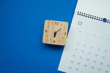 close up of calendar and alarm clock on the blue table background, planning for business meeting or travel planning concept