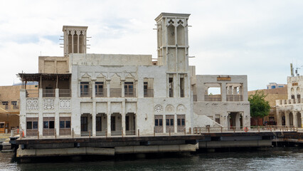 Fototapeta premium Beautiful street of Dubai old city or town or old village Al Seef Khor in Al Fahidi neighborhood, United Arab Emirates. Waterfront promenade along bank of Dubai Creek
