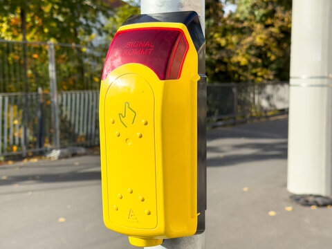 Yellow pedestrian push button with braille on city street for crossing signal activation