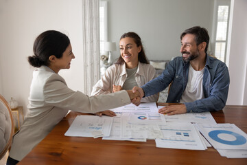 Grateful family couple shaking hands with female wealth consultant