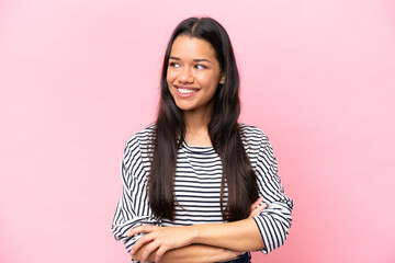 Young Colombian woman isolated on pink background looking to the side and smiling