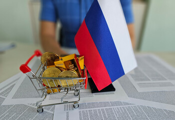 Russian flag displayed with gold coins and bars in a shopping cart on financial documents cryptocurrency bitcoin