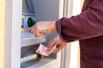 Obraz premium Young caucasian man at outdoors using an ATM