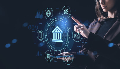 Woman interacting with banking hologram interface showing digital finance icons and data visualization on futuristic dark blue background concept..