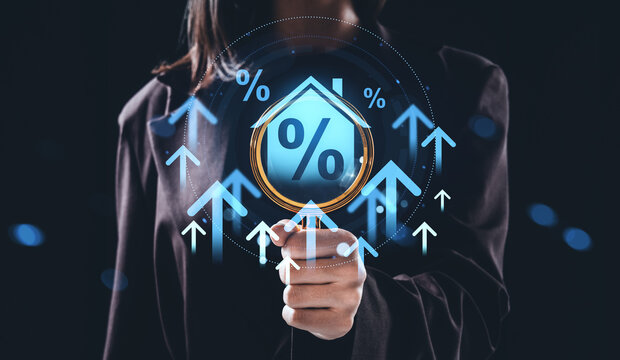 Business person holding magnifying glass over hologram of house and percent symbol with upward arrows representing rising interest rates concept. - Powered by Adobe