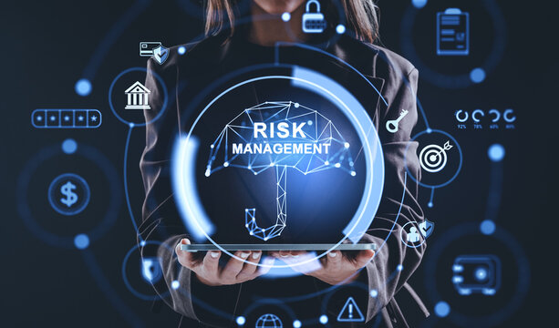 Businesswoman holding tablet with glowing hologram umbrella labeled risk management surrounded by finance and security icons on dark background concept.. - Powered by Adobe