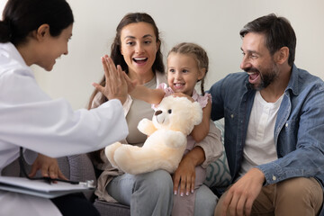 Joyful little girl giving high five to smiling female doctor
