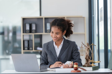 An American woman is a legal litigation attorney. A female lawyer is in a law firm, drafting contracts and reviewing client case details to study and find a solution to win the case.