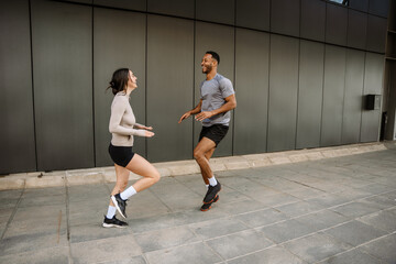 Fototapeta premium Male and female athletes laughing and running in place while raising their knees high