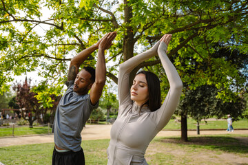 Man and woman athletes meditating with closed eyes and holding hands together above head