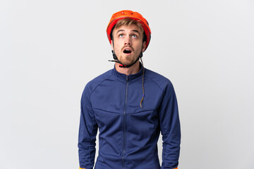 Young cyclist blonde man isolated on white background looking up and with surprised expression