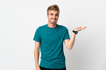 Young handsome man isolated on white background holding copyspace imaginary on the palm to insert an ad