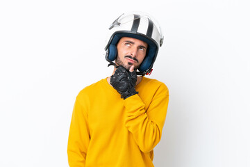 Fototapeta premium Young caucasian man with a motorcycle helmet isolated on white background having doubts