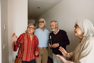 Fototapeta premium A group of four friends standing and looking away while talking and one of them holding a bottle