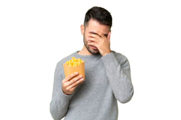Young caucasian man holding fried chips over isolated chroma key background with tired and sick expression