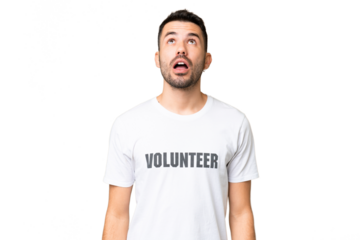 Young volunteer caucasian man over isolated chroma key background looking up and with surprised expression