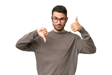 Young handsome caucasian man over isolated background making good-bad sign. Undecided between yes...