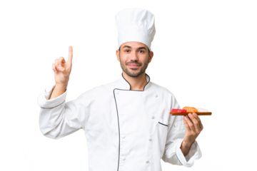 Young caucasian chef holding a sushi over isolated background pointing up a great idea
