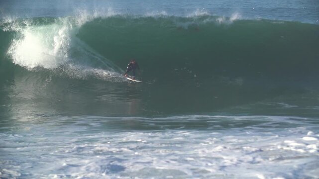 Super slow motion surfer riding a huge wave at the wedge