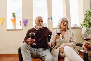 A man and a woman are holding glasses and sitting on a chair while she talks