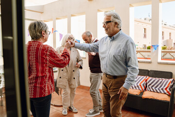 A man and a woman hold hands while dancing near two friends