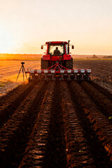 Farmer in tractor working field at sunset