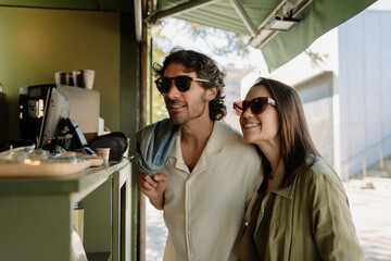 Fototapeta premium A man and a woman smile and look at the counter while he holds the outerwear over his shoulder