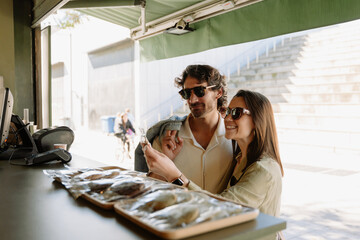 A man and a woman look at the package she is holding and smile